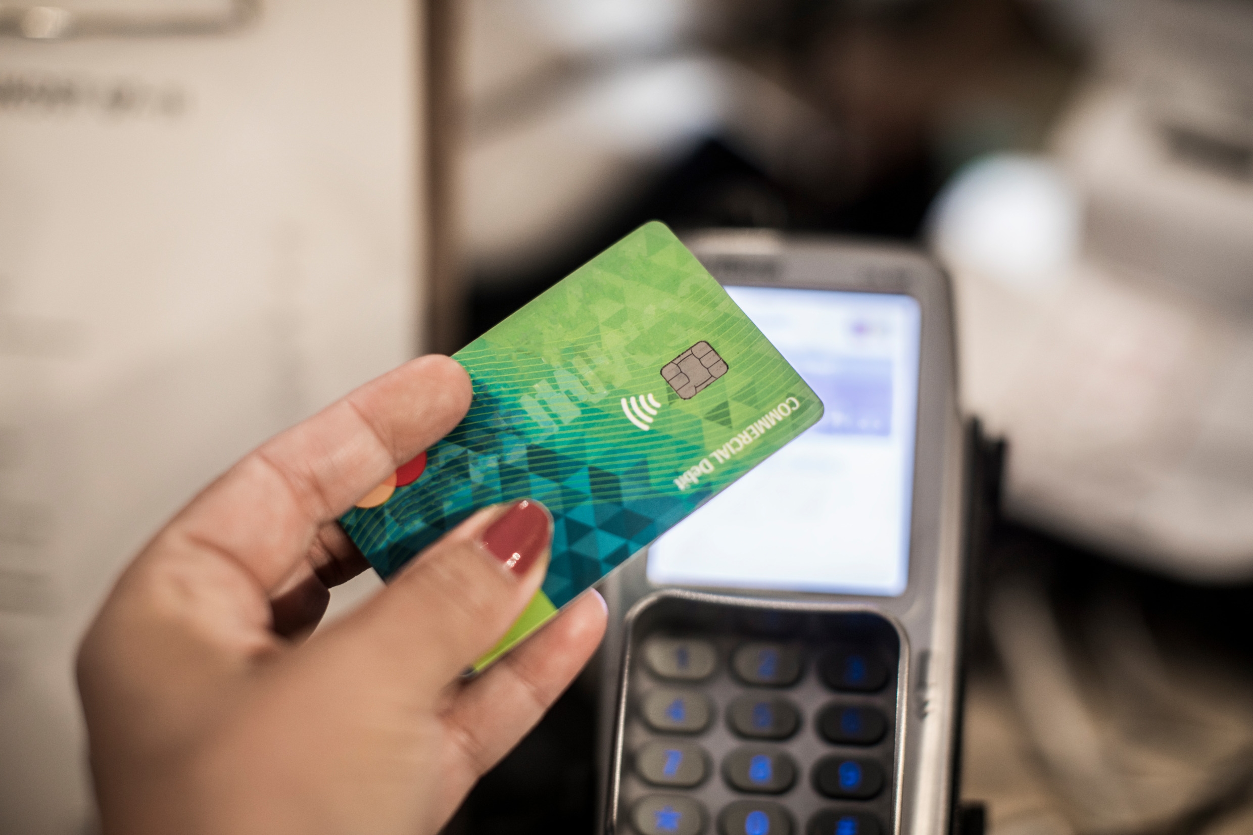 En hand håller ett kreditkort mot en kortterminal.