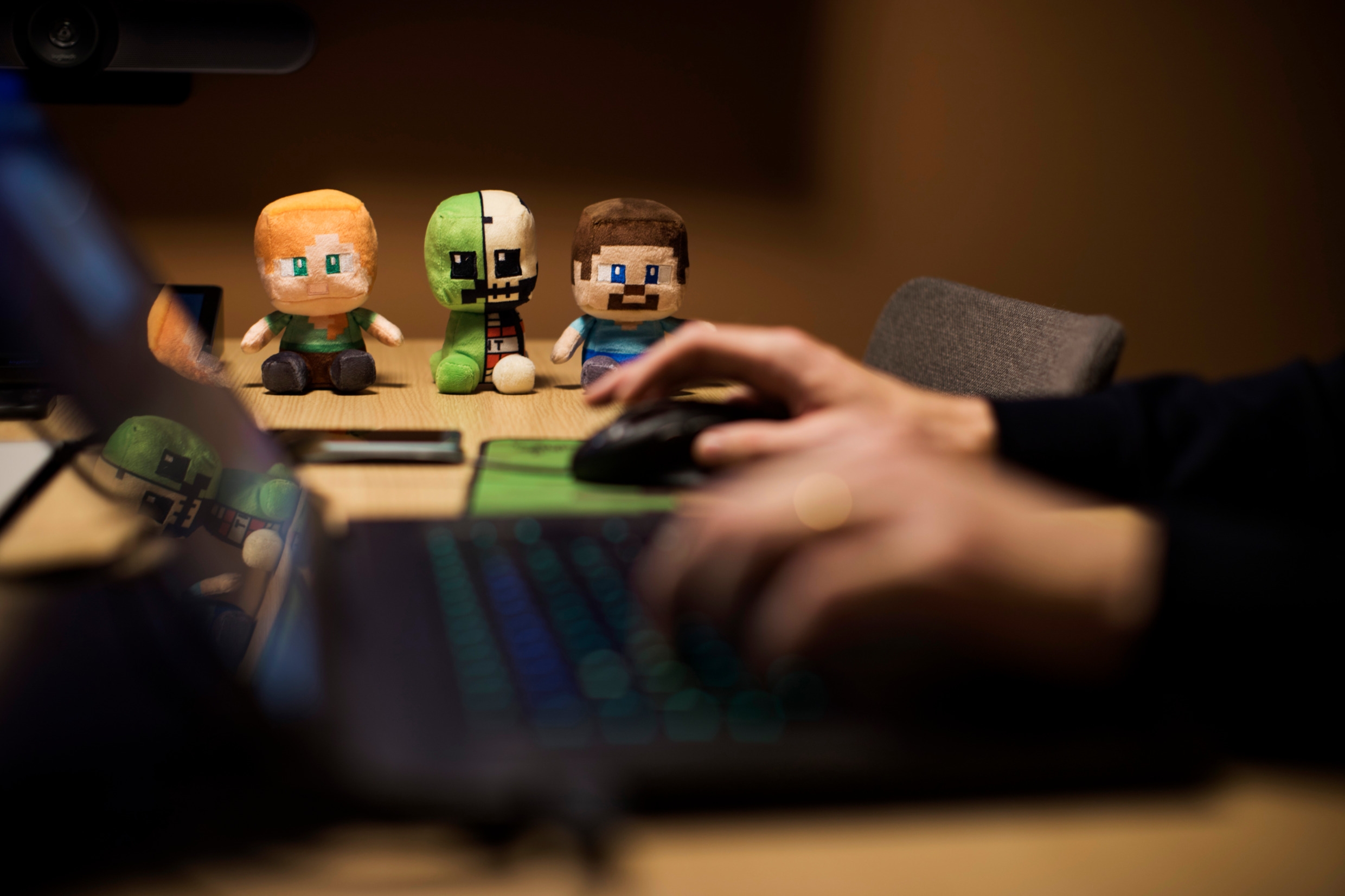 Tre små figurer förställande gubbar i ett spel som sitter på ett bord bredvid en laptop och mus