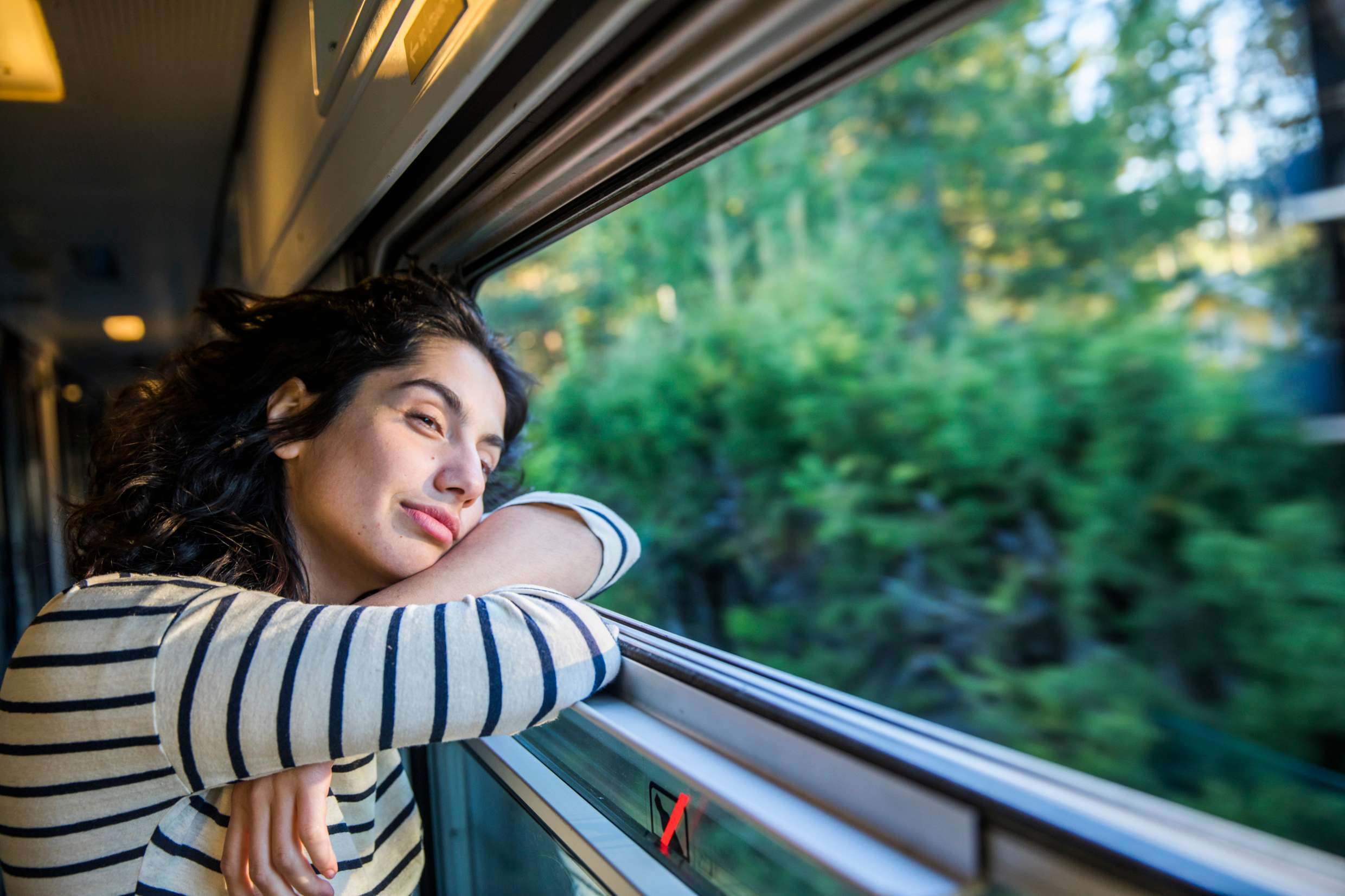 Kvinna på tåget lutar sig på händerna mot fönstret och tittar ut.