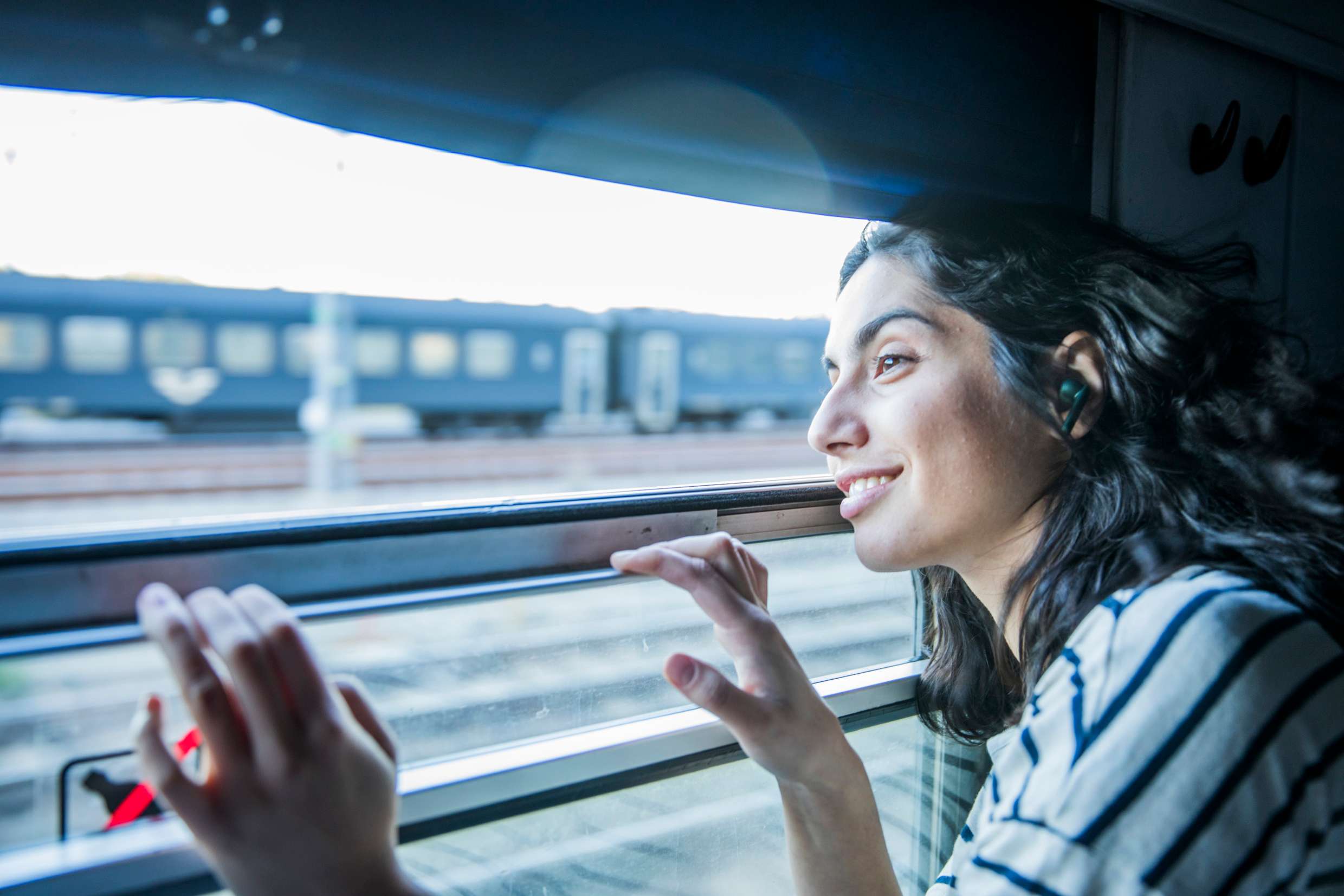 En kvinna ler och tittar ut genom ett fönster på tåget .
